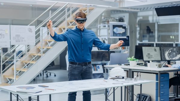 Engineering Software Developer Wearing Virtual Reality Headset Uses Gestures to Interact with Augmented Reality while Designing Industrial Engine Model in Modern Facility.