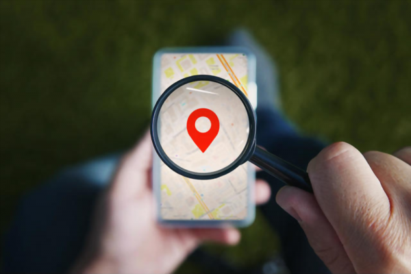 Shot of male hands holding magnifying glass with the red icon of geo-location