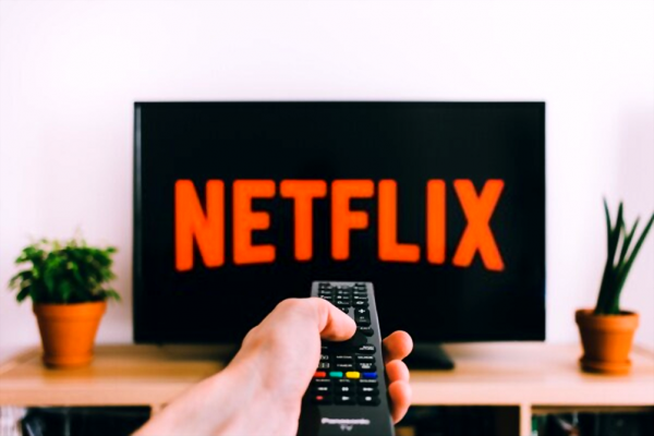 A man holding remote while watching Netflix.