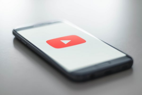 Photo of a phone with the youtube app open, all white and showing the youtube logo, placed on a white surface