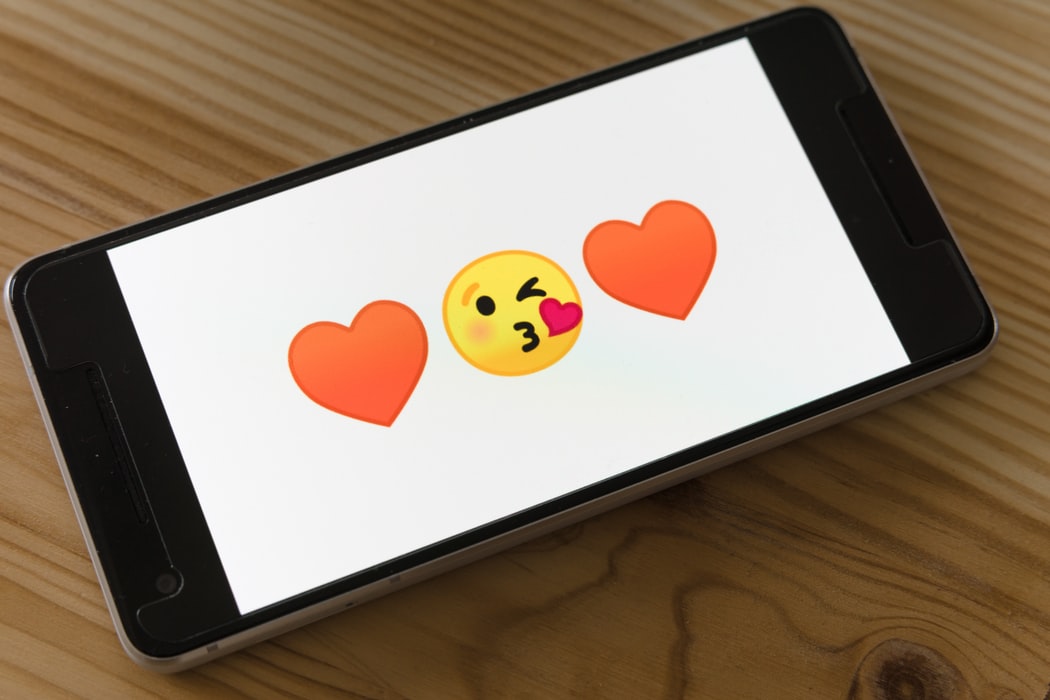 A cell phone with emojis commonly used on dating sites