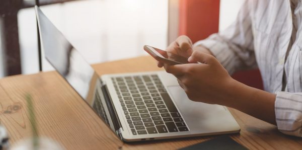 Woman Using Phone and Laptop