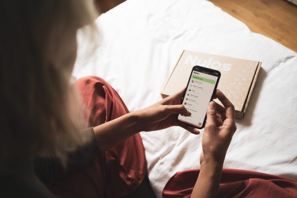 A girl holding her phone while on the bed